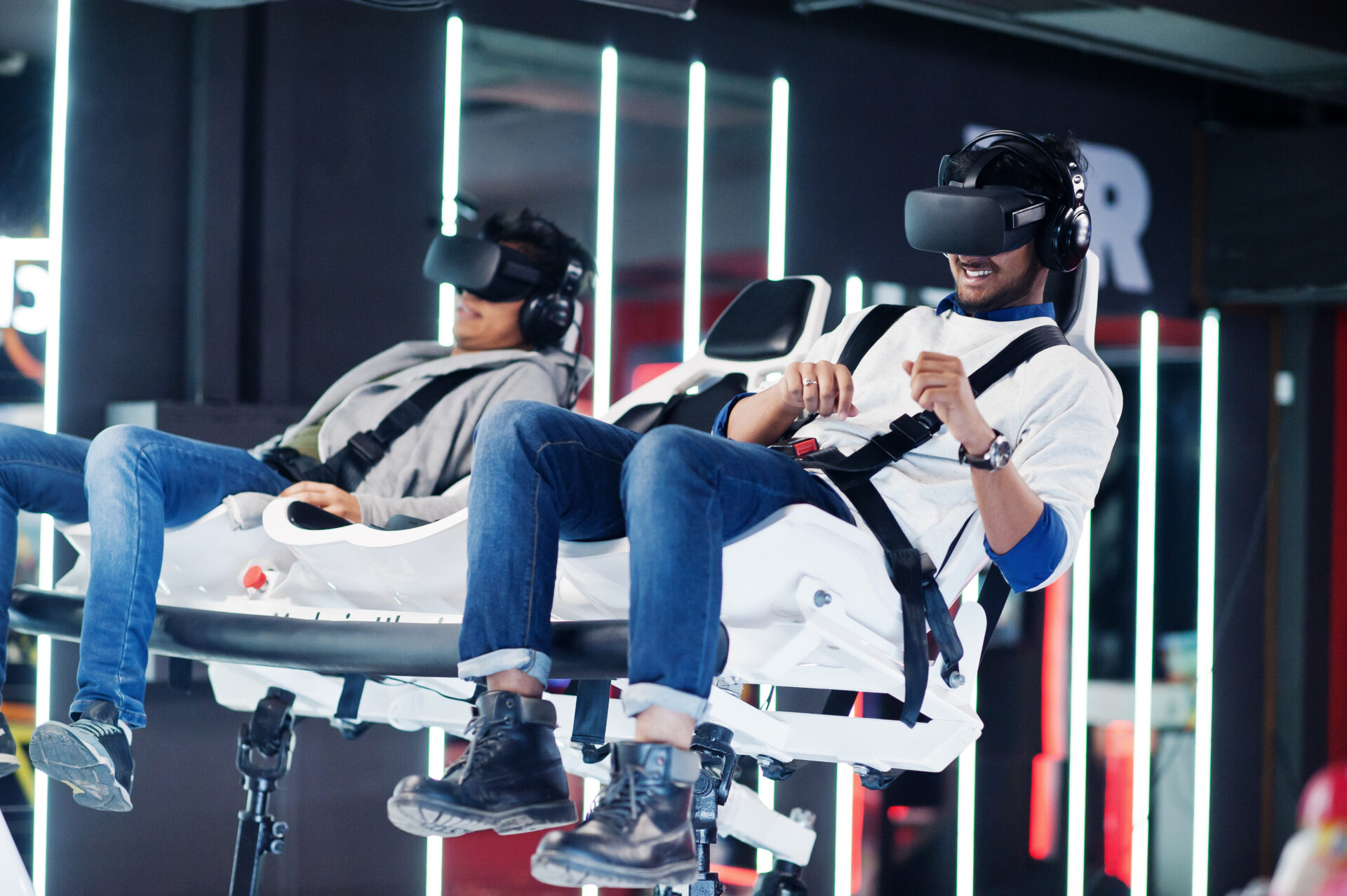 Two young indian people having fun with a new technology of a vr headset at virtual reality simulator.